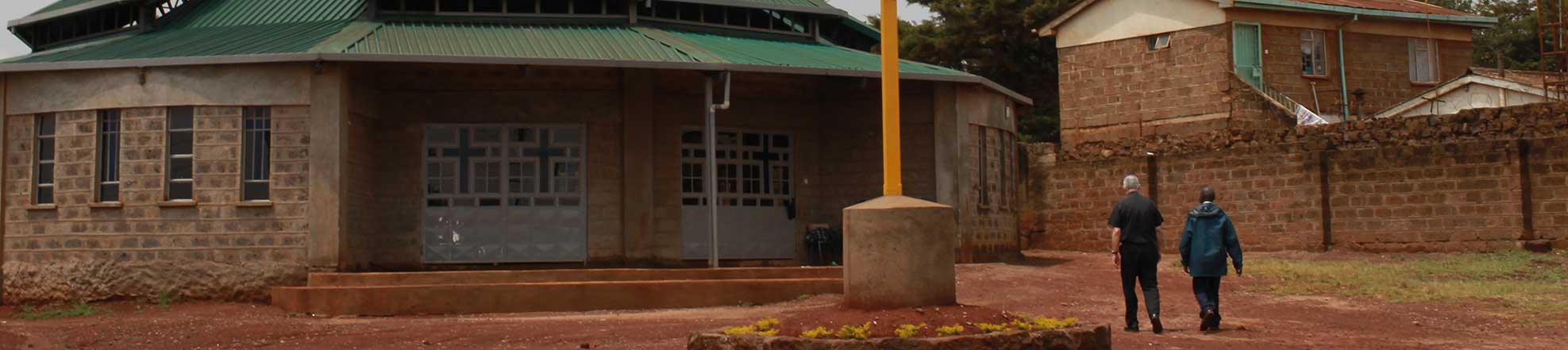 priest and a man walking by a church in Africa